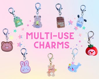Puede incluir: Una colección de amuletos multiusos con varios diseños lindos, incluyendo una rana, un oso, una barra de chocolate, un conejo y una ballena. Cada amuleto tiene un cierre plateado. El texto "MULTI-USE CHARMS" se muestra en rosa.