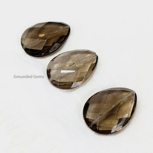 Peut inclure: Trois perles en forme de goutte de quartz fumé facettées. Les perles sont de couleur brun clair et ont une finition lisse et polie.