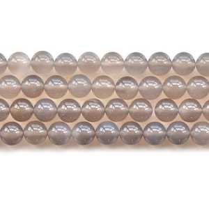 May include: Strand of grey gemstone beads. The beads are round, smooth, and have a polished, reflective surface. The beads are a neutral grey colour, with subtle variations in tone. The beads are strung together, ready for jewellery making.