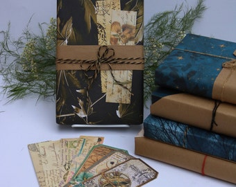 May include: A black and gold gift wrapped book with a brown twine bow. The book is wrapped in paper with a leaf pattern and has a vintage look. The book is sitting on a table with other wrapped gifts.