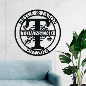 Könnte beinhalten: Schwarzes Metallschild mit Familiennamen, den Namen "Bryce & Jason", dem Nachnamen "Townsend" und dem Jahr "EST. 2024". Das runde Design zeigt einen großen Buchstaben "T" und dekorative florale Elemente.