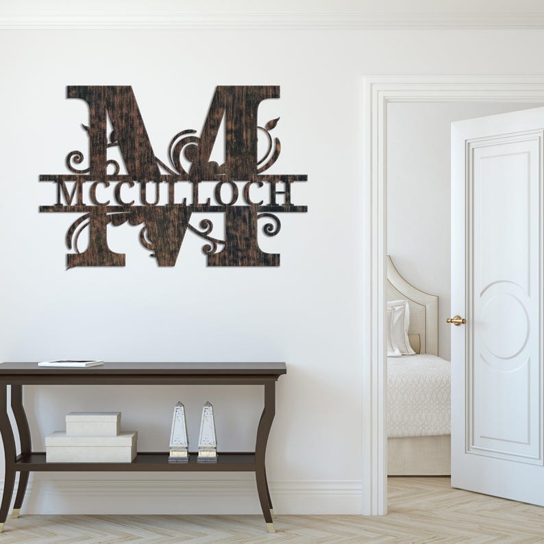 Peut inclure: Une enseigne murale en bois avec la lettre "M" et le nom "MCCULLOCH" d&eacute;coup&eacute;s. L'enseigne a une finition brun fonc&eacute; vein&eacute;e de bois et des ornements d&eacute;coratifs. Elle est fix&eacute;e sur un mur blanc.