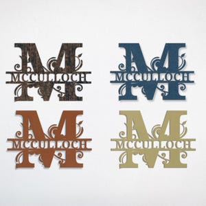 Peut inclure: Quatre enseignes de nom de famille en bois de diff&eacute;rentes couleurs : marron fonc&eacute;, bleu marine, cuivre et or. Chaque enseigne pr&eacute;sente la lettre "M" avec le nom "McCulloch" et des ornements d&eacute;coratifs.