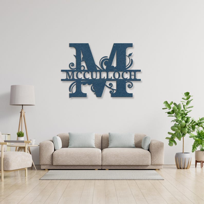 Peut inclure: Une d&eacute;coration murale en m&eacute;tal bleu repr&eacute;sentant la lettre "M" avec le nom "MCCULLOCH" en dessous. Le design comprend des ornements d&eacute;coratifs. L'&oelig;uvre est affich&eacute;e sur un mur blanc au-dessus d'un canap&eacute; beige.