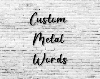 May include: Black metal words spelling "Custom Metal Words" against a white brick wall background. The words are in a cursive font, and the image is well-lit.