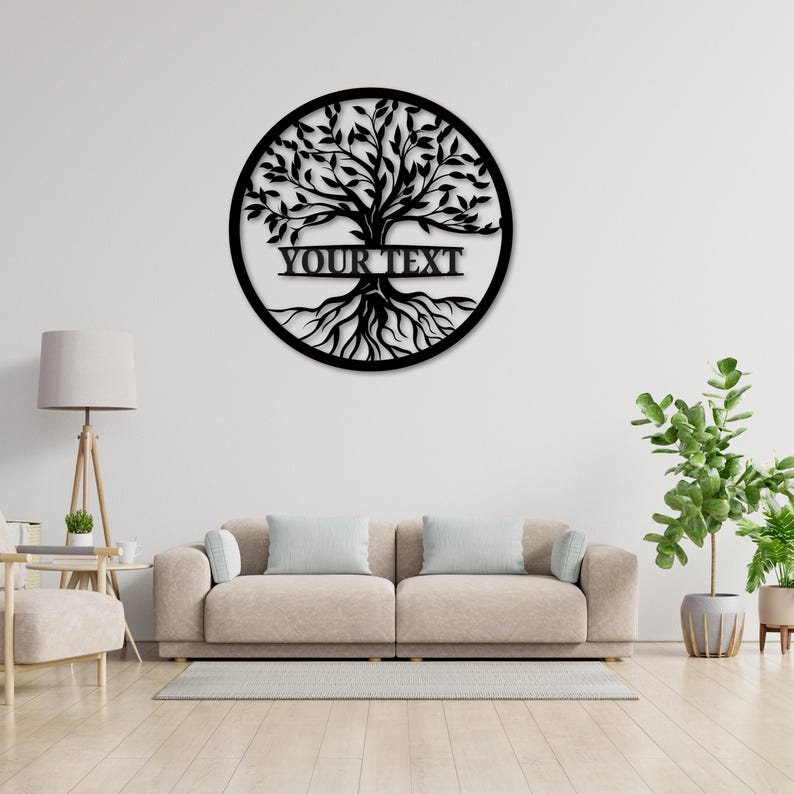 K&ouml;nnte beinhalten: Schwarzes Metall-Wandbild, Baum des Lebens, kreisf&ouml;rmig. Das Design zeigt einen detaillierten Baum mit Bl&auml;ttern, &Auml;sten und Wurzeln, mit dem Text "YOUR TEXT". Das Kunstwerk h&auml;ngt an einer wei&szlig;en Wand &uuml;ber einem beigen Sofa.