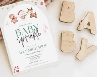 May include: A white invitation card with a green and white 'Baby Sprinkle' announcement for Ally Michaels. The card features a winter theme with gingerbread men, reindeer, and snowflakes. The text reads 'Please join us for a Baby Sprinkle honouring Ally Michaels, February 20th | 1:00pm, The Michaels Residence, 123 anywhere st., City, State, Zip, RSVP to Danielle at 123-456-7000'.