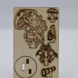 May include: A wooden cutout of a cartoon character with a mushroom hat, holding a magnifying glass and a bottle with a feather. The character is standing next to a dragon and a telescope. There is also a mushroom and a round cutout with two holes.