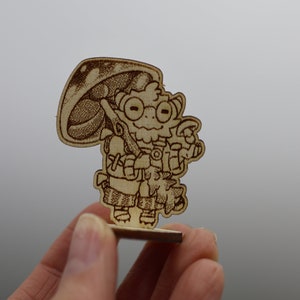 May include: A wooden figurine of a cartoon character with a mushroom cap, wearing a backpack and holding a stick. The character has large eyes and a friendly expression.