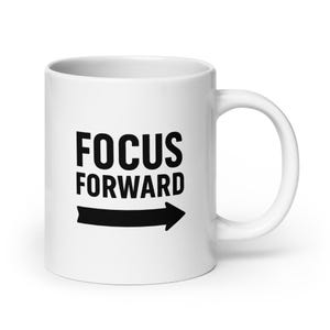 Pode incluir: Caneca de cerâmica branca com uma seta preta apontando para a direita e o texto "FOCUS FORWARD" impresso na frente.