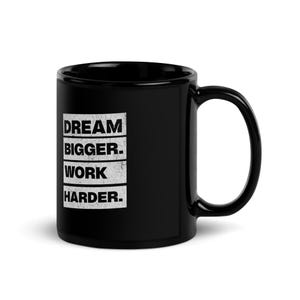 May include: Black ceramic coffee mug with white text that reads "DREAM BIGGER. WORK HARDER."