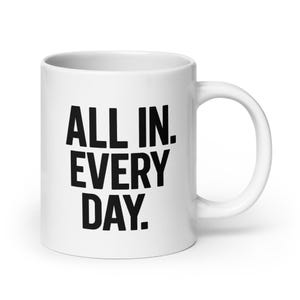 May include: White ceramic coffee mug with black text that reads "ALL IN. EVERY DAY."