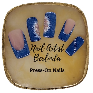 May include: Five press-on nails with a denim design. The nails are arranged in a hand shape on a light brown surface. The text "Nail Artist Berlinda Press-On Nails" is printed below the nails.