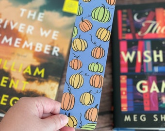 May include: A blue bookmark with a pattern of orange and green pumpkins. The bookmark is about 6 inches long and 2 inches wide.