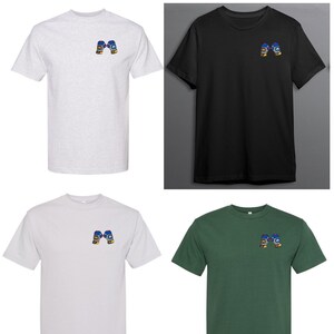 Op de afbeelding: Vier T-shirts in verschillende kleuren, elk met een klein geborduurd beeld van twee bokshandschoenen op de linker borst. De T-shirts zijn in grijs, zwart, wit en groen.