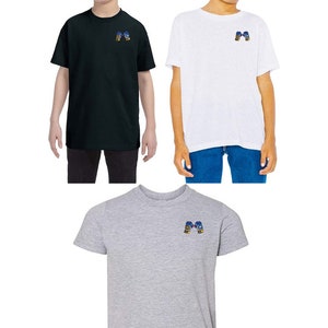 Op de afbeelding: Drie T-shirts voor kinderen in zwart, wit en grijs met een blauwe en gele bokshandschoen afbeelding op de voorkant.