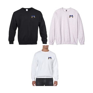 Op de afbeelding: Drie sweatshirts in zwart, wit en grijs met een klein geborduurd ontwerp van twee bokshandschoenen op de linkerborst.