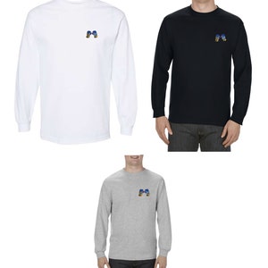 Op de afbeelding: Drie T-shirts met lange mouwen in wit, zwart en grijs met een klein geborduurd ontwerp van twee bokshandschoenen op de linkerborst.