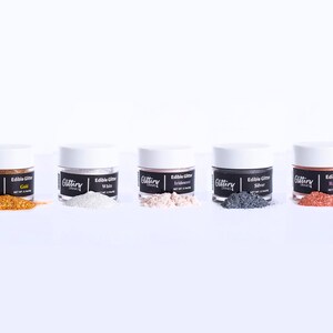 May include: Five small jars of edible glitter in various colors: gold, white, iridescent, silver, and rose gold. Each jar has a black label with the word "Glittery" and the color of the glitter.