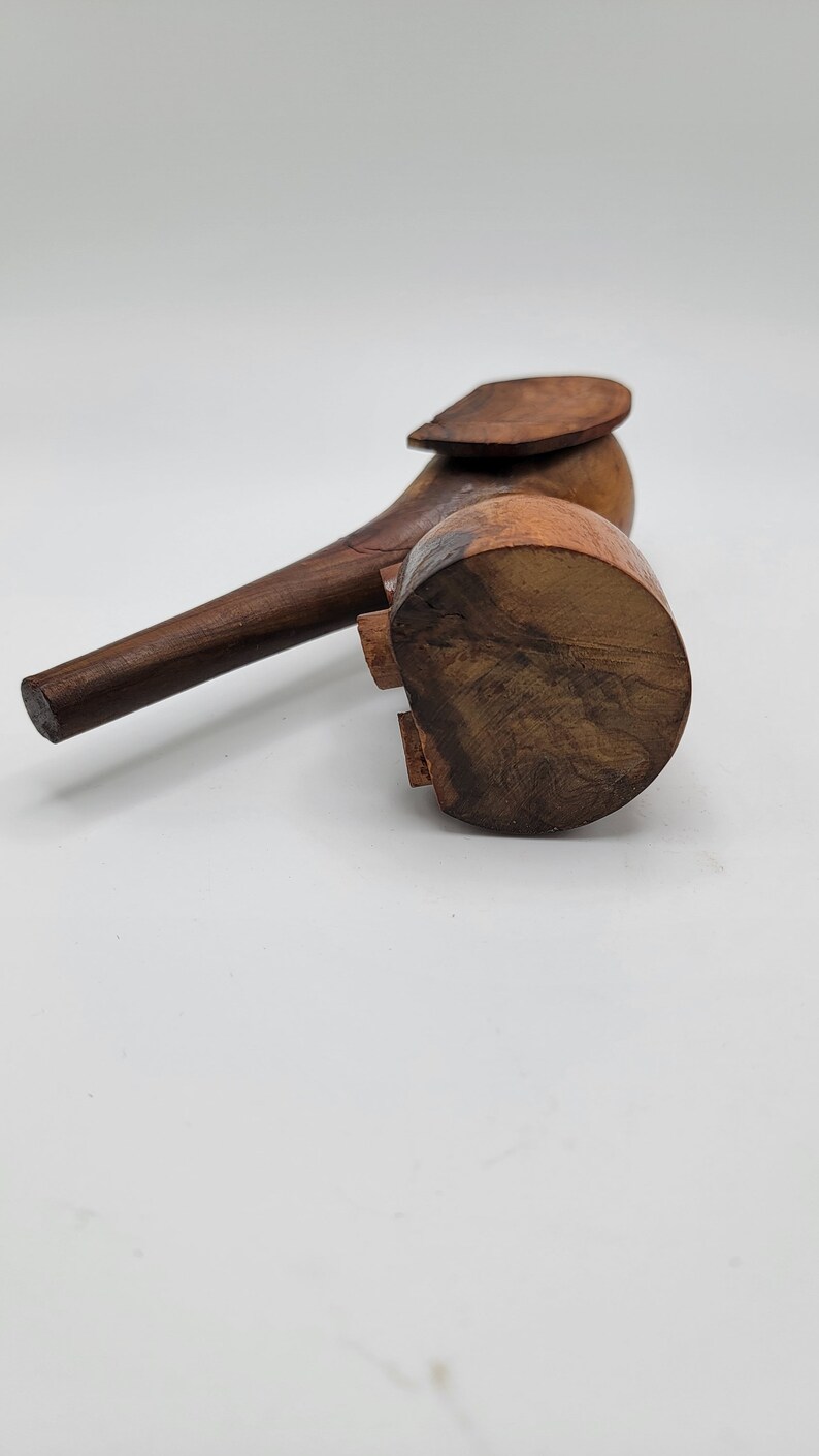 May include: A wooden elephant figurine with a brown finish. The elephant has a long trunk and a raised ear. The figurine is standing on a white surface.