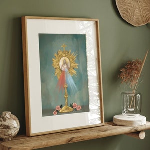 Puede incluir: Una impresión enmarcada de una imagen religiosa que representa a Jesucristo en un halo dorado con rayos de luz. La imagen está sobre un fondo azul y verde con flores rosas.