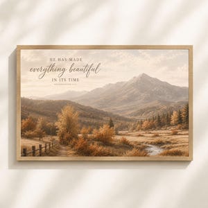 May include: A rectangular wall art print in a light wood frame featuring a mountain landscape with autumn trees, a small stream, and a wooden fence. The text HE HAS MADE everything beautiful IN ITS TIME ECCLESIASTES 3:11 is printed in dark brown.