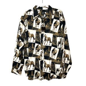 Pode incluir: Camisa de manga comprida com padrão de cavalos. A camisa apresenta um design repetido de cavalos castanhos, edifícios agrícolas e camiões sobre um fundo a preto e branco. A camisa está pendurada num cabide branco.