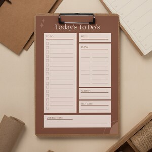 May include: A brown clipboard with a to-do list titled "Today's To Do's". The list includes sections for "To Do", "Date", "Plans", "Activity", "Self-Care", and "One Big Thing".