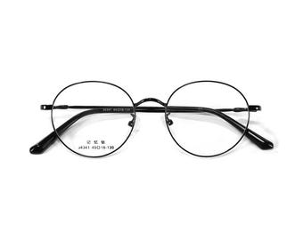 May include: Black round-frame eyeglasses with clear lenses. The glasses have a thin metal frame and arms. The text "34341 49018-139" is printed on the frame. The overall design is minimalist and modern.