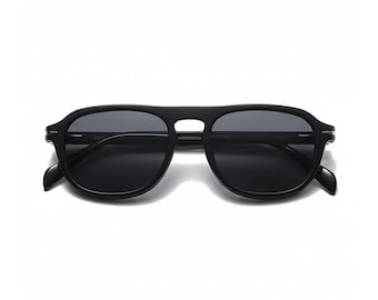 May include: Black sunglasses with a classic aviator design. The sunglasses have a thick, black frame and dark lenses. The bridge of the sunglasses is a keyhole shape. The sunglasses are set against a white background.