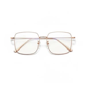 May include: Square-framed eyeglasses with a gold-colored metal frame. The lenses are clear, and the glasses have a minimalist design. The glasses are set against a white background.