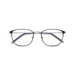May include: Eyeglasses with a black frame and clear lenses. The glasses have a rounded shape and a silver bridge. The temples are black and attach to the frame with small silver hinges. The lenses are clear and reflect light.