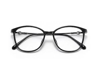 Puede incluir: Gafas negras de forma ovalada con un diseño delicado. Las monturas son de color negro brillante, con un sutil elemento decorativo en las patillas. Las lentes son transparentes y el estilo general es moderno y elegante.