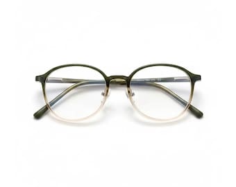 May include: Round-framed eyeglasses with a two-tone design. The top half of the frames is a dark green, transitioning to a light gold color on the bottom. The lenses are clear, and the glasses are set against a white background.