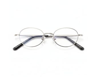 May include: Silver-framed eyeglasses with clear lenses and black temple tips. The glasses have a classic, round shape and a minimalist design. The frame is made of a shiny, metallic material.