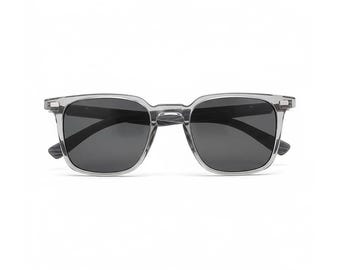 Könnte beinhalten: Graue quadratische Sonnenbrille mit dunklen Gläsern. Die Sonnenbrille hat einen durchscheinenden grauen Rahmen und dunkelgraue Gläser. Die Bügel haben eine Holzmaserung. Die Sonnenbrille wird auf weißem Hintergrund präsentiert.