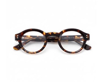 May include: Round-framed eyeglasses with a tortoiseshell pattern. The glasses have a classic design with a dark brown and amber color scheme. The frame features small rivets on the temples and the text "19 42020-142 C11 CE".