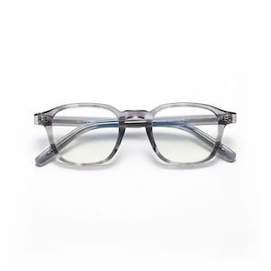 May include: A pair of grey, square-framed spectacles with clear lenses. The spectacles have a subtle, translucent appearance and are set against a white background. The frames are a neutral grey colour.