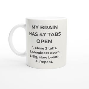 以下が含まれることがあります： 白いセラミックマグカップ、曲がったハンドル付き。 マグカップには、黒で「MY BRAIN HAS 47 TABS OPEN」というテキストと、指示「1. 3つのタブを閉じます。 2. 肩を下ろします。 3. 大きくゆっくりと呼吸します。 4. 繰り返します。」が表示されています。