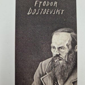 May include: Black and white portrait of Fyodor Dostoevsky, a Russian novelist, with a beard and a serious expression. The image is on a dark background with the name "FYODOR DOSTOYEVSKY" written in white.