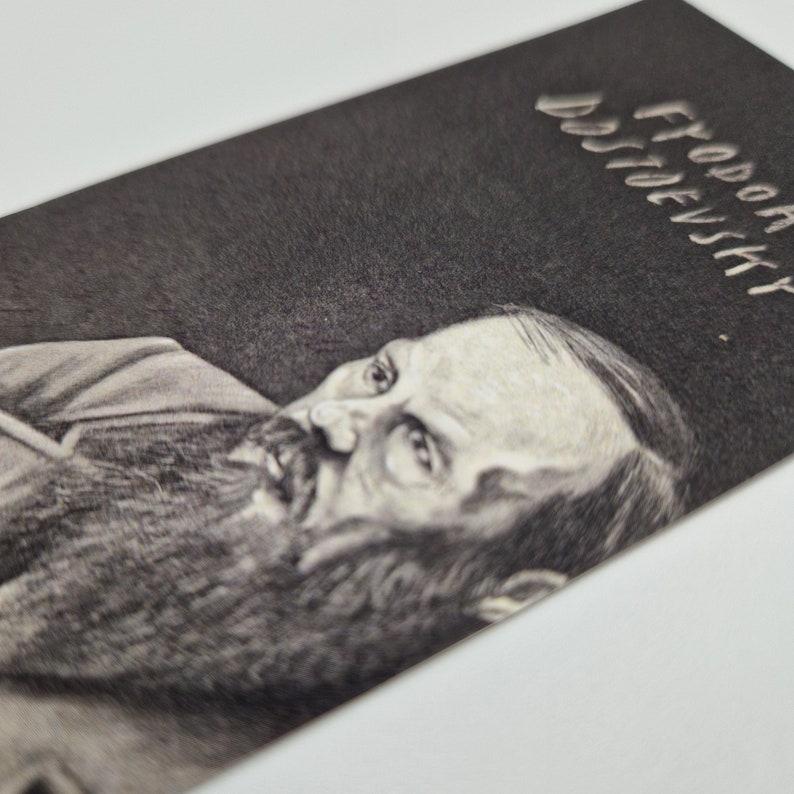 May include: A black and white pencil drawing of Fyodor Dostoevsky, a famous Russian author. The drawing is on a dark background with the name "Fyodor Dostoevsky" written in white lettering at the top.
