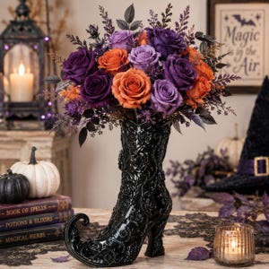 May include: A black ceramic boot-shaped vase with an intricate embossed floral pattern, filled with a vibrant bouquet of orange and purple roses, dark foliage, and small purple filler flowers, creating a striking contrast in color and texture.