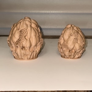 Peut inclure: Deux objets d&eacute;coratifs beiges imprim&eacute;s en 3D. Les objets pr&eacute;sentent un design textur&eacute; et organique avec un motif en nid d'abeille. Le plus grand objet est &agrave; gauche et le plus petit &agrave; droite. Les objets sont pos&eacute;s sur une surface blanche.