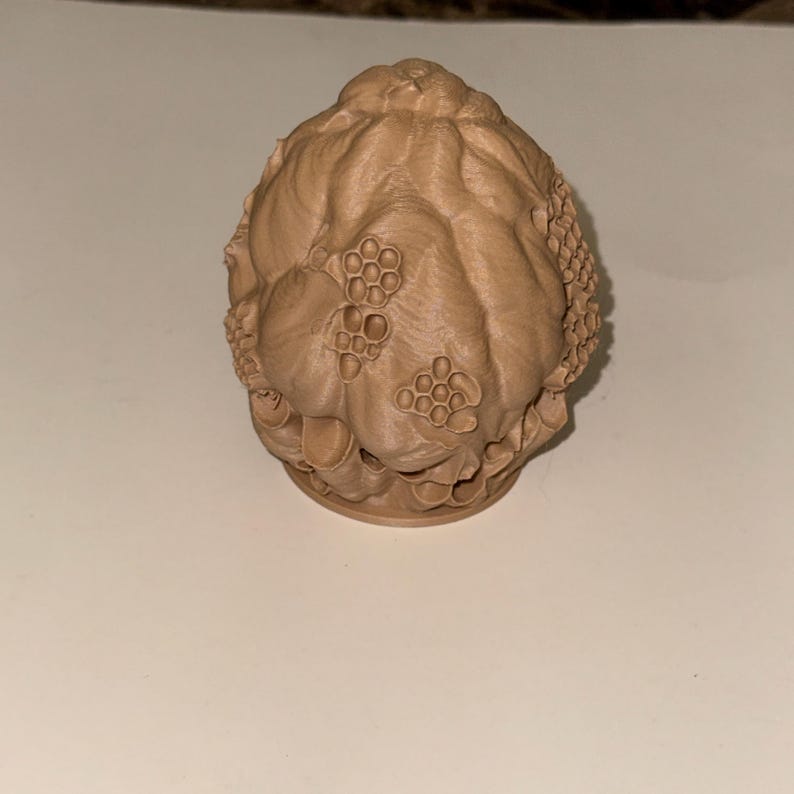 Peut inclure: Objet d&eacute;coratif marron clair imprim&eacute; en 3D avec une surface textur&eacute;e. L'objet a une forme arrondie avec des motifs en nid d'abeille et d'autres d&eacute;tails organiques. La base est circulaire et le design g&eacute;n&eacute;ral est complexe et d&eacute;taill&eacute;.