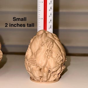 Peut inclure: Un petit objet d&eacute;coratif brun clair avec une surface textur&eacute;e, ressemblant &agrave; un artichaut stylis&eacute; ou &agrave; une forme botanique similaire. Il mesure environ 5 cm de haut. Le texte "Small 2 inches tall" est inclus.
