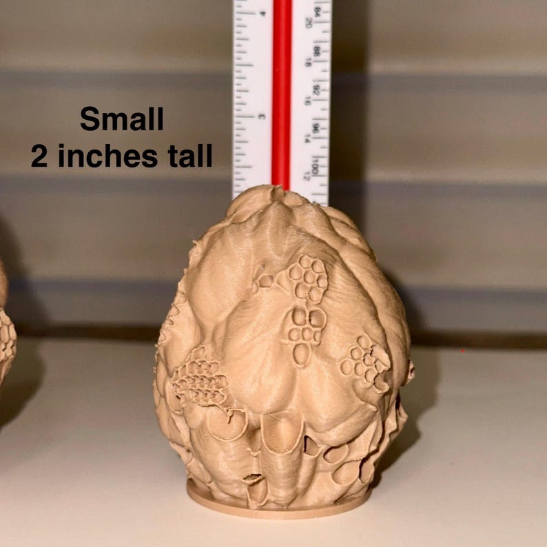 Peut inclure: Un petit objet d&eacute;coratif brun clair avec une surface textur&eacute;e, ressemblant &agrave; un artichaut stylis&eacute; ou &agrave; une forme botanique similaire. Il mesure environ 5 cm de haut. Le texte "Small 2 inches tall" est inclus.
