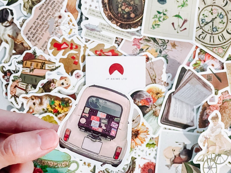 May include: A collection of vintage-style stickers featuring various designs. Includes a sticker of a light pink car with luggage, floral illustrations, dog illustrations, and a teacup. The stickers are in a variety of shapes and sizes.