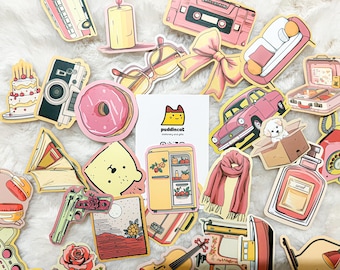 May include: A collection of colorful stickers featuring various designs, including a pink donut, a yellow refrigerator, a pink car, a cat, a book, a camera, a couch, a birthday cake, a cassette tape, a bottle of perfume, a phone, a scarf, a gun, a lamp, a sewing machine, a musical instrument, and a landscape scene. The stickers are all on a white background.