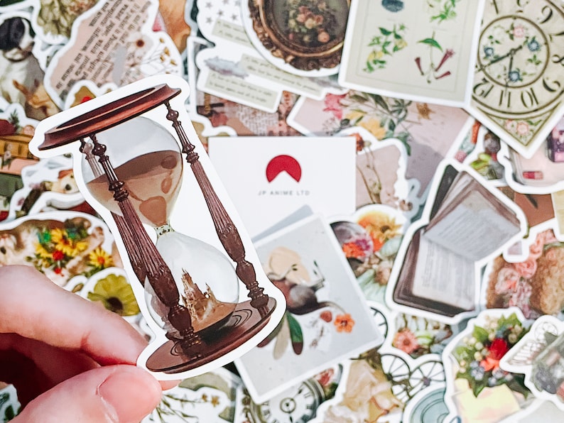 May include: A sticker featuring a detailed hourglass design with brown wooden supports and a clear glass center filled with sand. The sticker is surrounded by other vintage-themed stickers, including floral and antique elements.