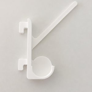 May include: A white plastic hook with a vertical spine, two rectangular mounting tabs on the left side, a circular cup-shaped holder at the bottom, and a long, angled support arm extending diagonally upward to the right.